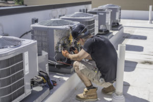 Hvac technician checking controls on a condenser